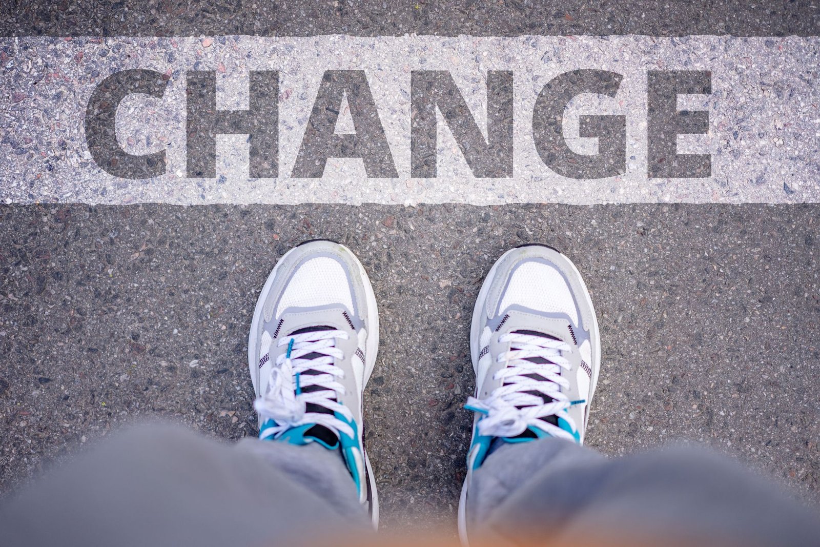 Close-up of a person standing on pavement stenciled with the word CHANGE